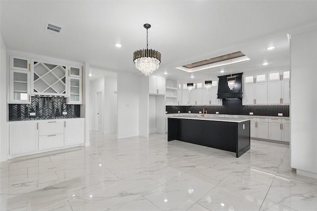 kitchen with premium range hood, tasteful backsplash, light marble finish floors, white cabinetry, and a sink