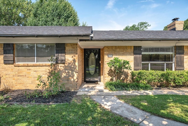 407 Sunset St, Malakoff, TX 75148 - view of exterior entry featuring brick siding, a chimney, a shingled roof, and a yard