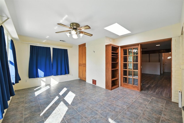3908 Windhaven Rd, Fort Worth, TX 76133 - empty room featuring a skylight, ceiling fan, and dark tile patterned flooring