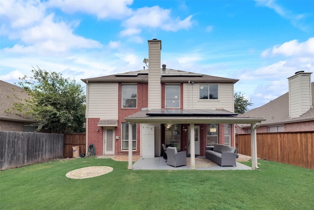 back of house with an outdoor hangout area, brick siding, a patio, roof mounted solar panels, and a chimney