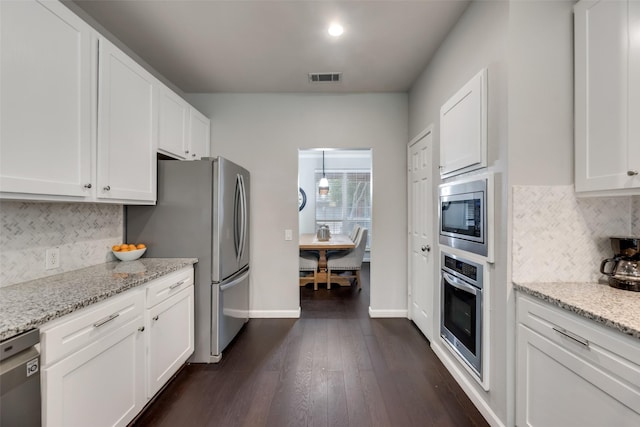 kitchen featuring stainless steel appliances, white cabinetry, light stone counters, and decorative backsplash