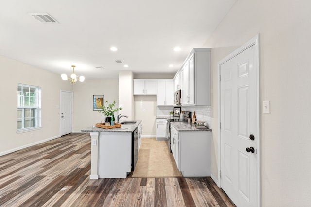 1504 Yale St, River Oaks, TX 76114 - kitchen with stainless steel appliances, a chandelier, light stone countertops, light wood-type flooring, and decorative backsplash