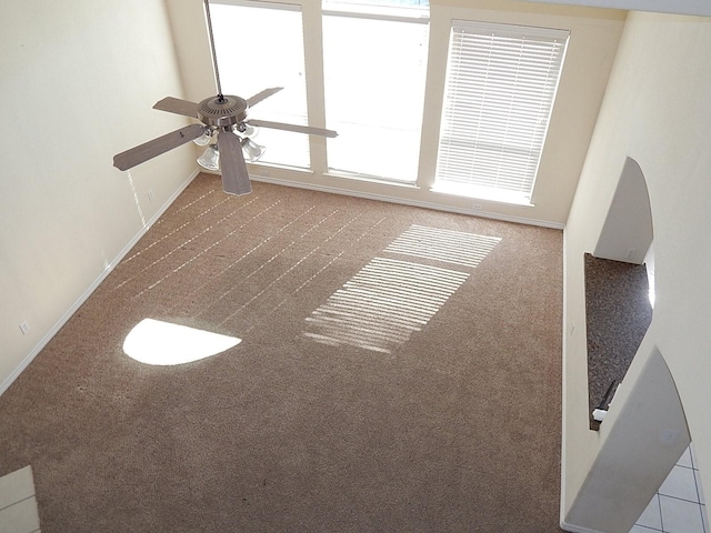 unfurnished living room featuring carpet flooring, a ceiling fan, and baseboards
