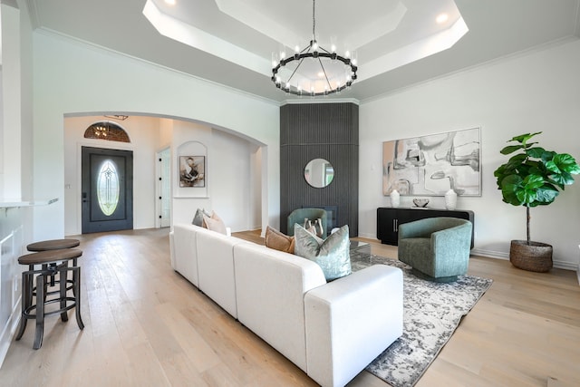 12809 Day Break Trl, Burleson, TX 76028 - living room featuring a chandelier, a raised ceiling, arched walkways, light wood finished floors, and ornamental molding
