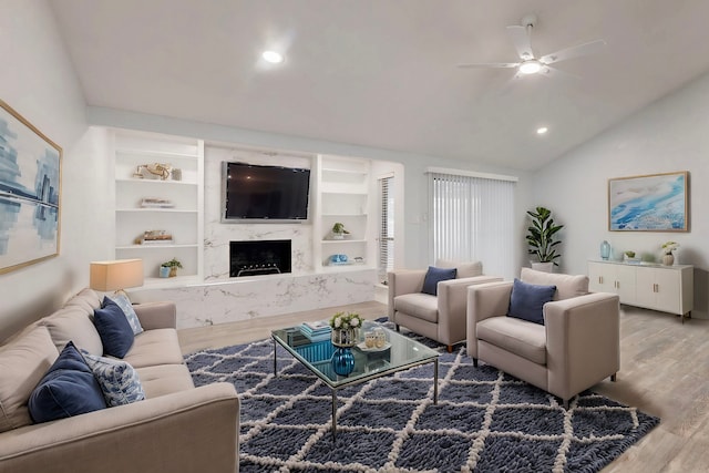 living area with wood finished floors, a ceiling fan, vaulted ceiling, recessed lighting, and a fireplace