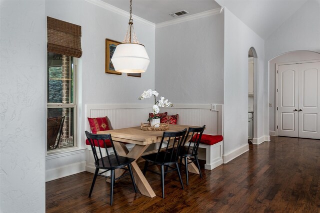 dining space featuring arched walkways, wood finished floors, breakfast area, ornamental molding, and baseboards