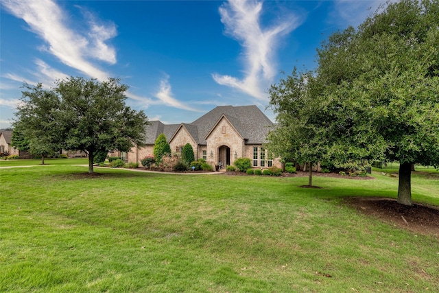 french country home featuring stone siding and a front yard