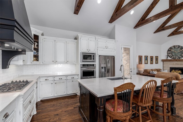 kitchen featuring stainless steel appliances, a sink, beam ceiling, light countertops, and custom range hood