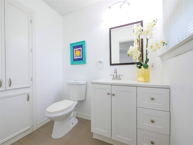 half bathroom featuring toilet, baseboards, vanity, and tile patterned floors