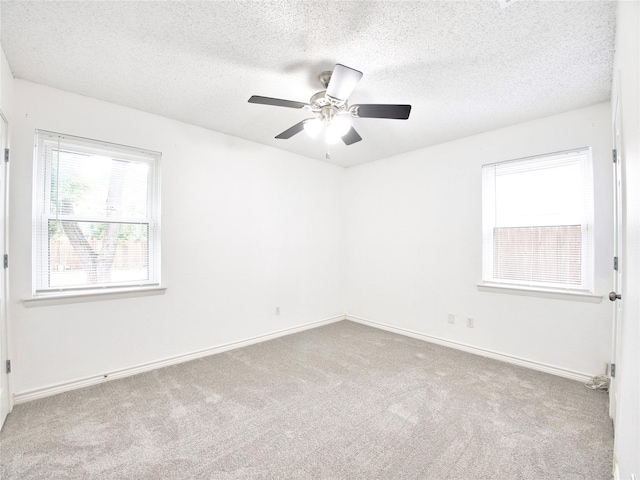 empty room with carpet floors, a textured ceiling, ceiling fan, and baseboards