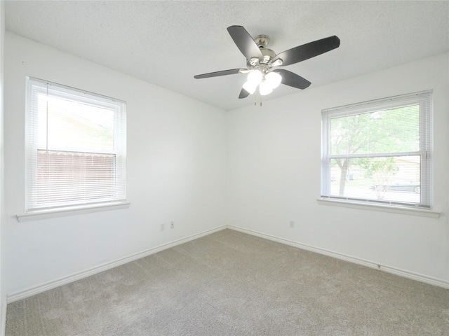 unfurnished room featuring light carpet, baseboards, ceiling fan, and a textured ceiling