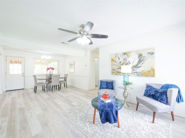 living area with ornamental molding, wood finished floors, a textured ceiling, a chandelier, and ceiling fan