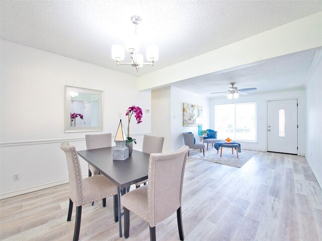 dining room with a textured ceiling, a chandelier, light wood finished floors, baseboards, and a ceiling fan