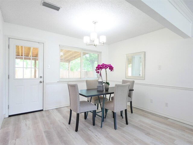 dining space with a chandelier, light wood-style flooring, a textured ceiling, and baseboards