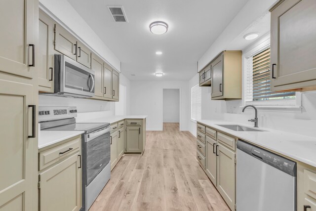 kitchen featuring stainless steel appliances, a sink, light countertops, light wood-style flooring, and recessed lighting