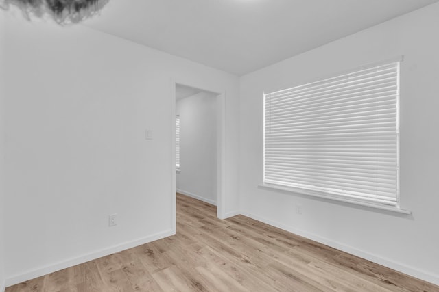 spare room featuring baseboards and light wood-type flooring