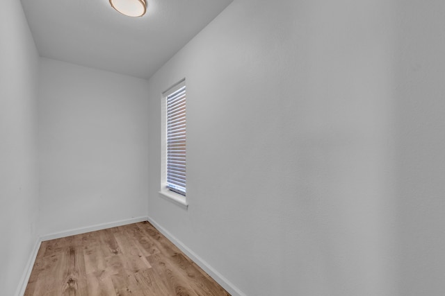empty room featuring light wood-style flooring, plenty of natural light, and baseboards