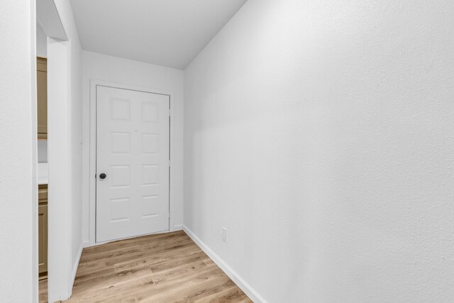 corridor with light wood finished floors and baseboards