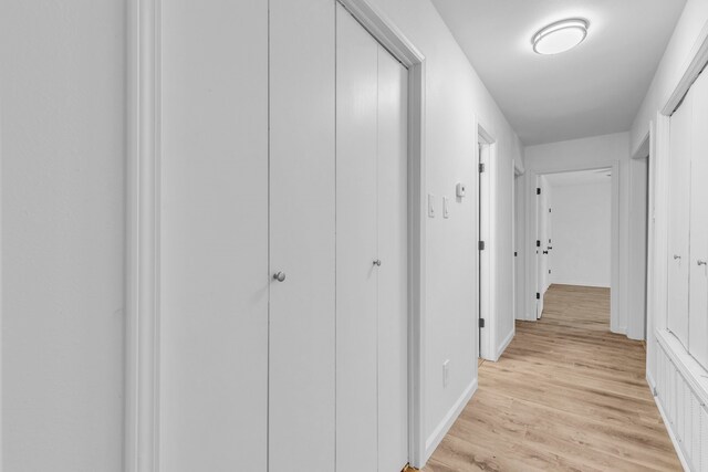 hall with light wood-type flooring and baseboards