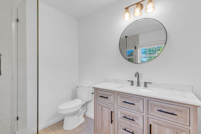 full bathroom featuring toilet, a shower with door, tile patterned floors, vanity, and baseboards