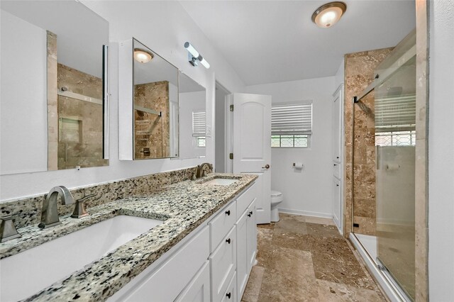 bathroom featuring toilet, a stall shower, baseboards, and double vanity
