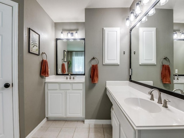 bathroom featuring baseboards, two vanities, and tile patterned floors