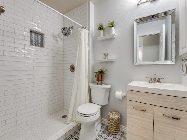 bathroom with toilet, vanity, a stall shower, and baseboards