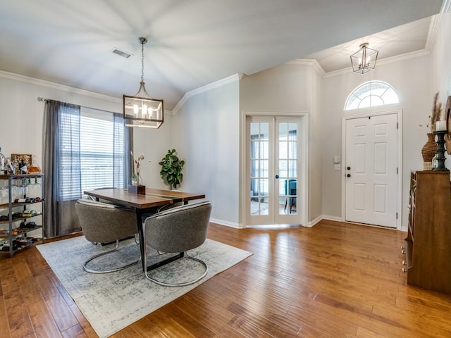 entryway featuring a chandelier, hardwood / wood-style floors, crown molding, vaulted ceiling, and baseboards