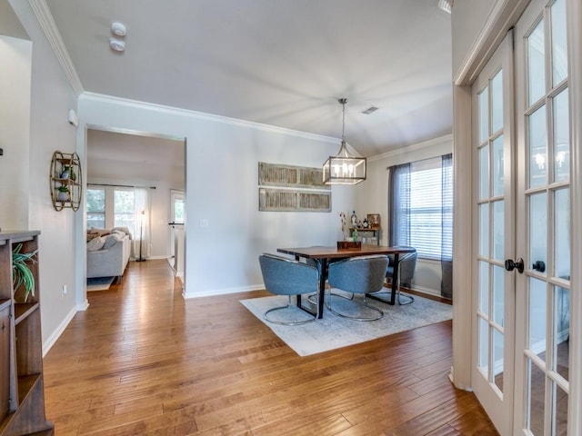 dining space featuring french doors, crown molding, baseboards, light wood-type flooring, and a chandelier