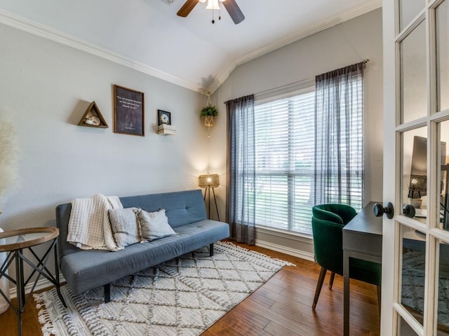 living area with a ceiling fan, lofted ceiling, ornamental molding, wood finished floors, and baseboards