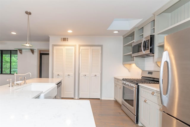 2850 Claudette Ave, Dallas, TX 75211 - kitchen featuring appliances with stainless steel finishes, a sink, open shelves, wood finished floors, and light countertops