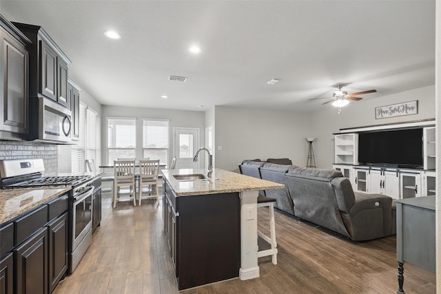 1206 Burlingame Dr, Cleburne, TX 76033 - kitchen with stainless steel appliances, a sink, ceiling fan, a center island with sink, and a kitchen bar