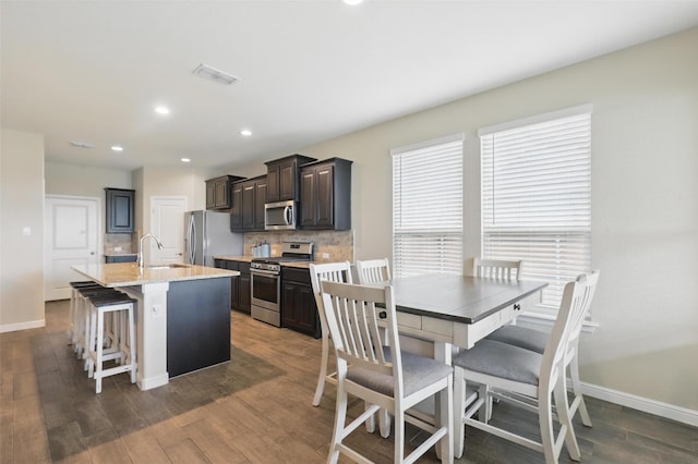 1206 Burlingame Dr, Cleburne, TX 76033 - kitchen featuring stainless steel appliances, a sink, an island with sink, tasteful backsplash, and baseboards