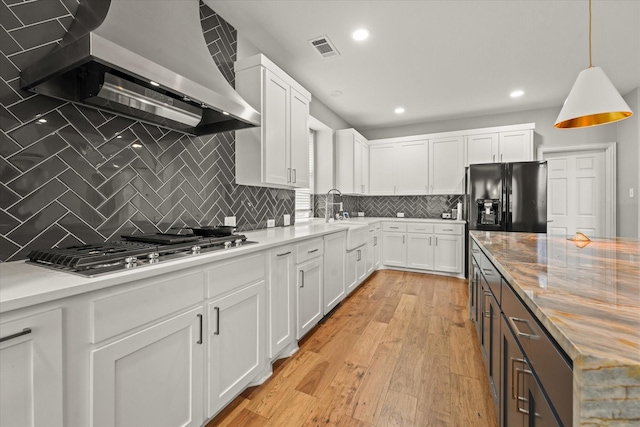 5610 Kensington Ct, Parker, TX 75002 - kitchen with wall chimney exhaust hood, black refrigerator with ice dispenser, stainless steel gas cooktop, white cabinets, and recessed lighting
