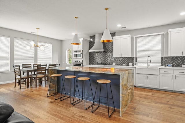 5610 Kensington Ct, Parker, TX 75002 - kitchen with wall chimney exhaust hood, oven, a sink, a center island, and a chandelier