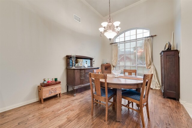 dining area with ornamental molding, a chandelier, light wood finished floors, a high ceiling, and baseboards