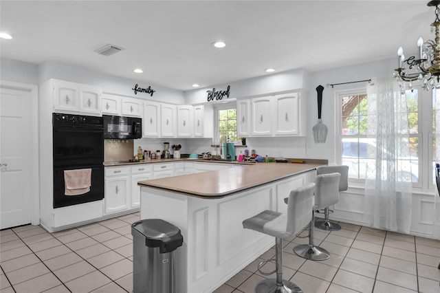 3205 Glasgow Ter, Arlington, TX 76015 - kitchen featuring black appliances, a breakfast bar, backsplash, light tile patterned flooring, and recessed lighting
