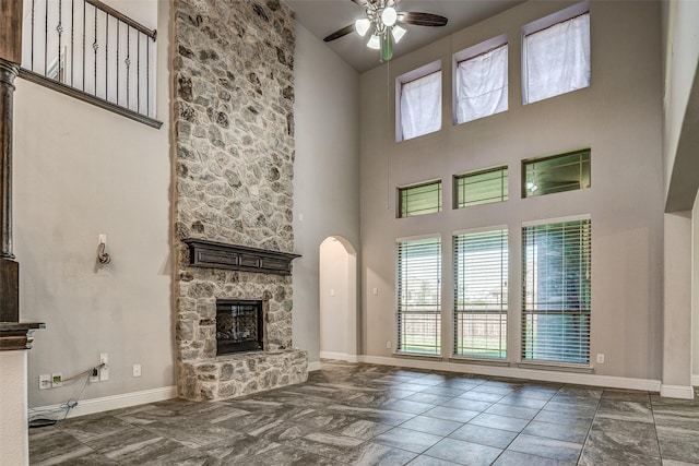 14015 Steadman Dr, Frisco, TX 75035 - unfurnished living room with a towering ceiling, a stone fireplace, ceiling fan, baseboards, and arched walkways