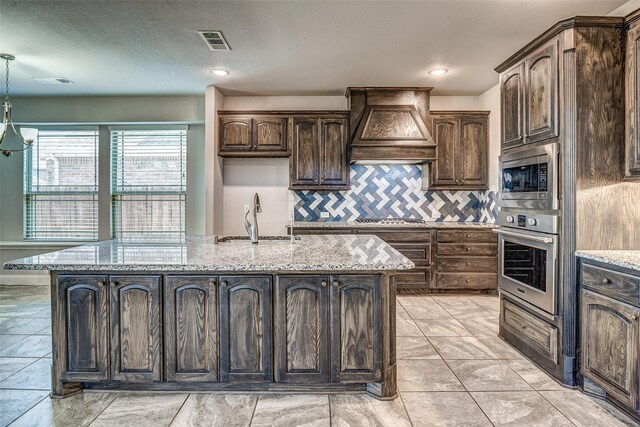 14015 Steadman Dr, Frisco, TX 75035 - kitchen featuring stainless steel appliances, a sink, custom exhaust hood, backsplash, and light stone countertops