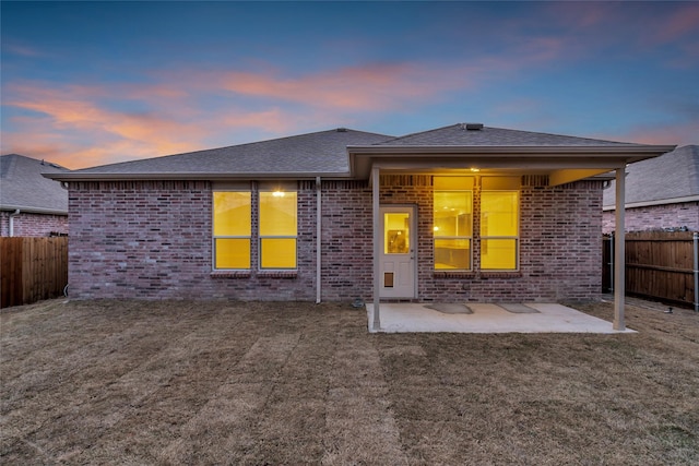 1321 Rivers Creek Ln, Little Elm, TX 75068 - back of property at dusk featuring brick siding, a patio area, and a shingled roof