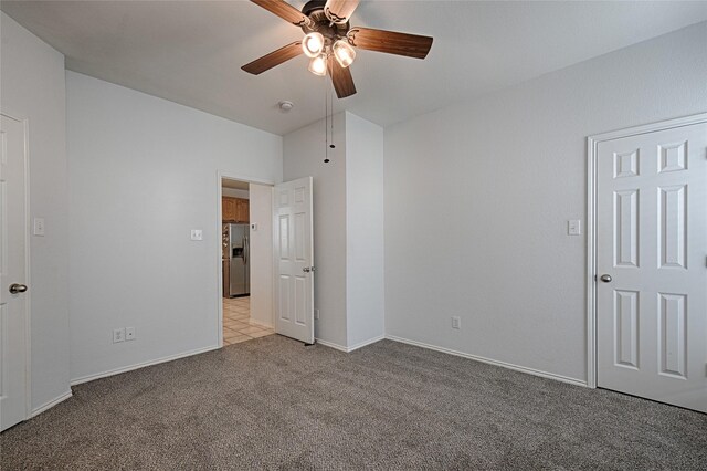 9912 Concord Dr, Providence Village, TX 76227 - unfurnished bedroom featuring stainless steel fridge with ice dispenser, light colored carpet, baseboards, and ceiling fan