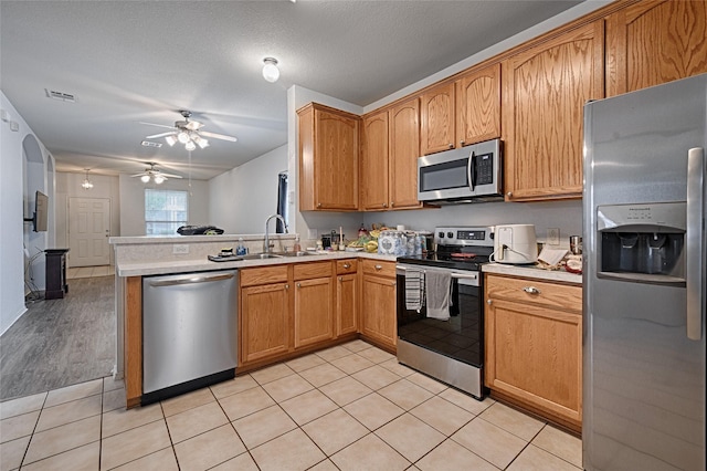 9912 Concord Dr, Providence Village, TX 76227 - kitchen with stainless steel appliances, a sink, light countertops, ceiling fan, and a peninsula