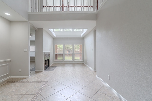 6913 Mccracken Ct, Fort Worth, TX 76132 - unfurnished living room featuring a tiled fireplace, baseboards, light tile patterned floors, and a high ceiling