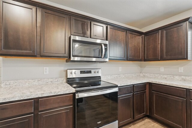 123 Rock Creek Ln, Terrell, TX 75160 - kitchen featuring appliances with stainless steel finishes, dark brown cabinets, light countertops, and light wood-style floors