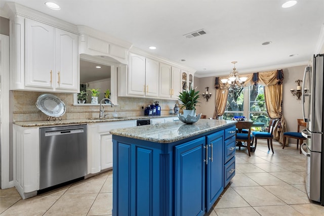 kitchen featuring stainless steel appliances, a sink, blue cabinetry, white cabinets, and a kitchen island