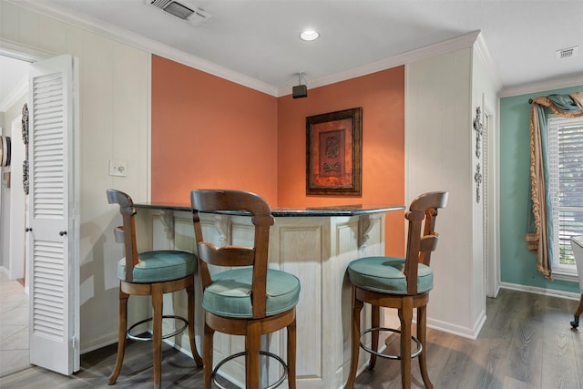 indoor dry bar featuring ornamental molding, baseboards, wood finished floors, plenty of natural light, and recessed lighting