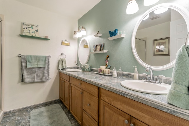 full bathroom with double vanity, an enclosed shower, baseboards, and stone finish floors