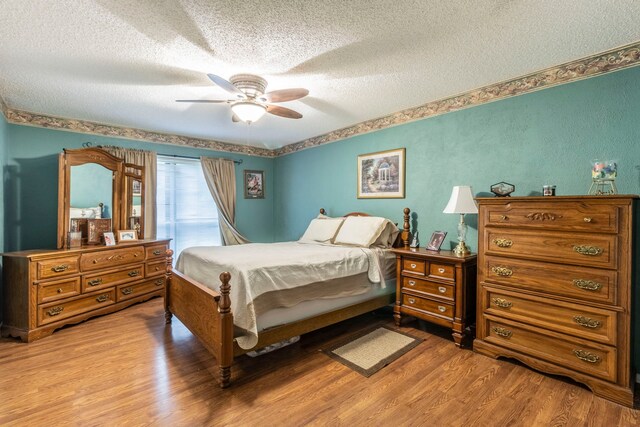 bedroom featuring a textured ceiling, light wood finished floors, and a ceiling fan