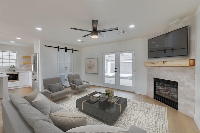 7319 Rutgers Dr, Dallas, TX 75214 - living area with a barn door, a ceiling fan, light wood-type flooring, recessed lighting, and a fireplace