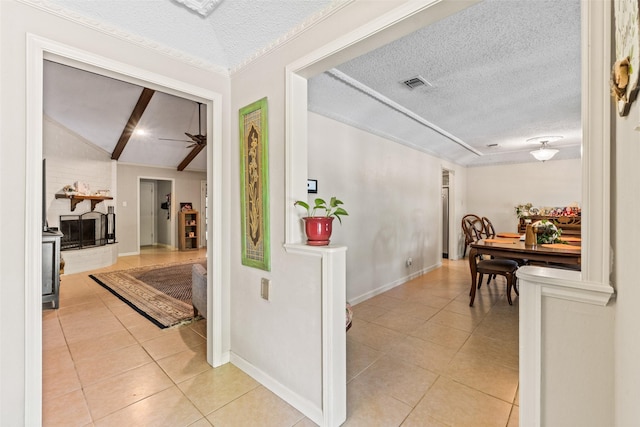 corridor featuring light tile patterned flooring, a textured ceiling, vaulted ceiling, and baseboards